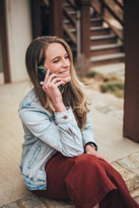 Business Coach Laura Schoenfeld on phone smiling talking about how to sell nutrition services